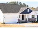 Attractive home with a two-car garage and covered front porch, showcasing a mix of siding and stone details at 818 Barbour Farm Ln, Four Oaks, NC 27524