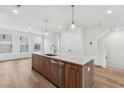 Modern kitchen island with quartz countertop, wood cabinets, and stainless steel sink at 448 Billingshurst Way, Knightdale, NC 27545