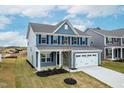 Charming two-story home featuring blue siding, black shutters, and a two-car garage at 8905 Stratus St, Willow Springs, NC 27592