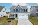 Charming two-story home featuring blue siding, black shutters, and a two-car garage at 8905 Stratus St, Willow Springs, NC 27592