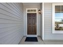 Dark brown front door with a sidelight and a black doormat at 18 Steppe Way, Garner, NC 27529