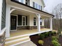 Inviting covered front porch featuring wooden flooring, white columns, stone accents, and views of the landscaped yard at 399 W Amber Oak Dr # 52, Selma, NC 27576