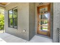 Charming covered porch with a modern wood and glass front door framed by gray brick and a window at 14020 Durant Rd, Raleigh, NC 27614