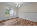 Dining room with natural light, wainscoting, and elegant chandelier over hardwood floors at 225 Whistlers Cv, Louisburg, NC 27549