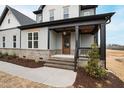 Covered front porch with stained wood door, brick steps, and black trim at 100 Firefly Ln, Louisburg, NC 27549