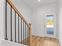 Bright entryway with hardwood floors, white walls, black metal handrail, and door leading to the outside at 953 Alma Railway Dr, Wake Forest, NC 27587
