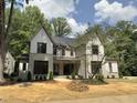 Charming two-story house with a gray brick and stone facade complemented by manicured landscaping and mature trees at 7208 Tanbark Way, Raleigh, NC 27615