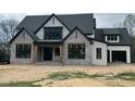 A modern farmhouse with stone accents, black trim, white siding, and a covered front porch under construction at 126 Harvest Ln, Pittsboro, NC 27312