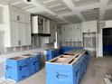A kitchen being built featuring white cabinets with black hardware and an island with blue protective covers at 126 Harvest Ln, Pittsboro, NC 27312