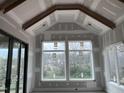 Bright living room featuring a vaulted ceiling, wooden beam, and large windows overlooking the backyard at 126 Harvest Ln, Pittsboro, NC 27312