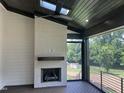 Covered outdoor patio featuring a brick fireplace, ceiling fan, and views of the backyard at 126 Harvest Ln, Pittsboro, NC 27312