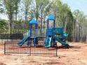 Community playground featuring slides and climbing equipment surrounded by a black metal fence at 195 Anise Ln, Garner, NC 27529