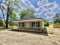 Single-story home featuring gray siding, black shutters, and a covered front porch provides a quaint curb appeal at 233 Jenkins St, Erwin, NC 28334