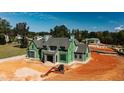 View of new construction home with gray shake roof, green exterior wrap and heavy equipment on unfinished lawn at 705 Parker Creek Dr, Raleigh, NC 27614