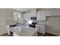 Well-lit kitchen features white cabinetry, stainless steel appliances, stone countertops, and stylish backsplash at 19 Longdale Dr, Graham, NC 27253
