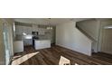 Open-concept living room and kitchen boasts an island, chandelier, and wood-style flooring throughout at 19 Longdale Dr, Graham, NC 27253