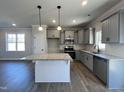 Well-lit kitchen with gray cabinets, stainless steel appliances, granite countertops, and an island at 17 S Mistflower St, Clayton, NC 27520