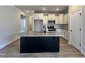 Kitchen featuring a central island, granite countertops, stainless steel appliances, and white cabinetry at 23 S Mistflower St, Clayton, NC 27520