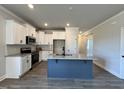 Modern kitchen with white cabinets, granite countertops, stainless steel appliances, and a blue island at 238 Bluejay St, Clayton, NC 27520