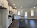 Bright kitchen featuring white cabinetry, granite counters, stainless steel appliances, and a gray island at 24 S Mistflower St, Clayton, NC 27520