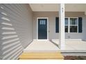 Inviting covered front porch with blue front door and decorative columns at 63 Falls River Ct, Broadway, NC 27505