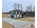 Modern farmhouse showcasing a spacious driveway, attached garage, and well-maintained landscaping at 2829 Faucette Ln, Burlington, NC 27217
