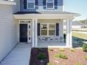 Charming front porch featuring stone accents, a black front door, and well-maintained landscaping at 56 Decatur Dr, Fuquay Varina, NC 27526