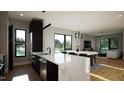 Open-concept kitchen features a large island, modern black appliances, and sleek lighting at 512 Gordon St # 1102, Durham, NC 27701