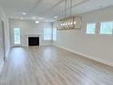 Spacious living room features modern light fixture, luxury vinyl flooring and a cozy fireplace at 85 Claude Creek Way, Smithfield, NC 27577