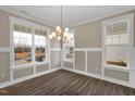 Bright dining room features a modern chandelier, wainscoting, and large windows at 1125 Brookfield Dr, Gibsonville, NC 27249