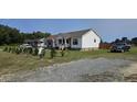 Well-maintained home with a large front yard, mature landscaping, and a gravel driveway at 3027 Nc Highway 210, Smithfield, NC 27577