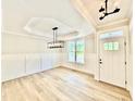 Elegant foyer with wainscoting, modern lighting, a tray ceiling, and light wood-look floors at 2613 Silver Gate Ct, Wake Forest, NC 27587