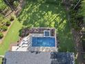 Aerial view of a private pool with a spa, surrounded by lush landscaping and a fenced yard at 7640 Falls Creek Ln, Raleigh, NC 27614