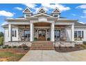Inviting covered porch with stone accents, wooden columns, rocking chairs, and a beautiful double door entrance at 1618 Ben Wilson Rd, Mebane, NC 27302