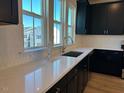Bright kitchen featuring quartz countertops, stainless steel sink, tile backsplash, and dark cabinetry at 1170 Holding Village Way, Wake Forest, NC 27587