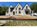 An eye-level exterior elevation features an off-white brick home under construction and a lot with a sign at 65 Firefly Overlook, Pittsboro, NC 27312