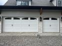 White garage doors with black hardware, complemented by a brick facade, enhancing the home's curb appeal at 65 Firefly Overlook, Pittsboro, NC 27312