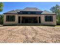 Expansive brick home featuring a covered porch, dark window frames, and a pristine roof against a clear blue sky at 65 Firefly Overlook, Pittsboro, NC 27312
