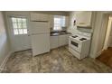 A bright kitchen with white cabinets and appliances, featuring a door to the outside at 1202 N Duke St, Durham, NC 27701