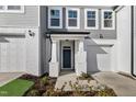 Charming townhome featuring a gray and white exterior, garage, and covered porch with a teal-colored front door at 553 Eversden Dr, Zebulon, NC 27597