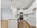 Modern kitchen featuring white cabinets, stainless steel appliances, a large island, and stylish pendant lighting at 553 Eversden Dr, Zebulon, NC 27597