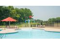 Community swimming pool with lounge chairs, umbrellas and a splash fountain at 553 Eversden Dr, Zebulon, NC 27597