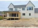 Rear exterior of new home with large windows, covered porch and unfinished back yard at 217 Dublin Rd, Raleigh, NC 27609