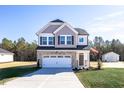 New two-story home featuring stone accents, a front-facing garage, a manicured lawn, and an American flag at 211 Wild Turkey Way, Lillington, NC 27546