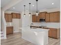 Modern kitchen with an island, stainless steel appliances, wood cabinets, and stylish pendant lighting at 211 Wild Turkey Way, Lillington, NC 27546