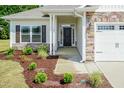 Inviting front entrance with a stone accent wall, a black front door and a well manicured lawn at 67 Decatur Dr, Fuquay Varina, NC 27526