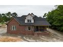 New brick house boasting a covered entry way and front porch with ample windows and a dark roof at 6352 River Rd, Fuquay Varina, NC 27526