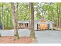 Charming home nestled among mature trees features a brick facade, white siding, and a gravel driveway at 128 Dixie Dr, Chapel Hill, NC 27514