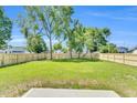 Large backyard featuring mature trees, lush green grass, and a new wooden fence at 306 E Godwin St, Dunn, NC 28334