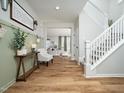 Inviting foyer with hardwood floors, staircase, sage green accent wall, and a view into the living room at 137 Shadowdale Ln, Rolesville, NC 27571